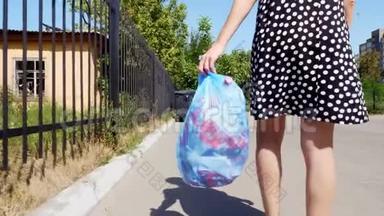 特写，后景，女孩手里拿着<strong>一包</strong>垃圾，扔出垃圾。 夏日炎炎。 生态